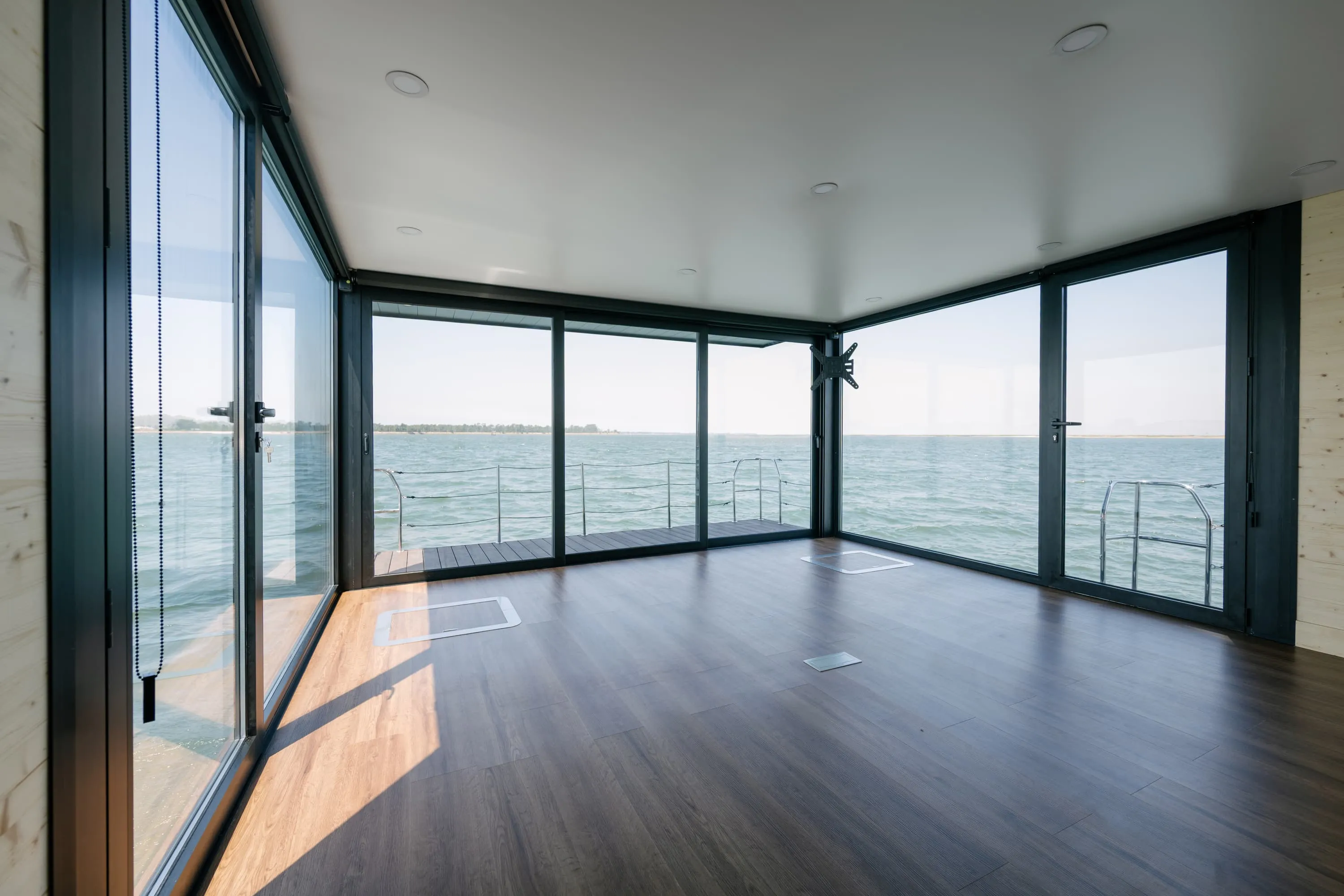 Empty interior of a floating office with panoramic glass walls overlooking the water